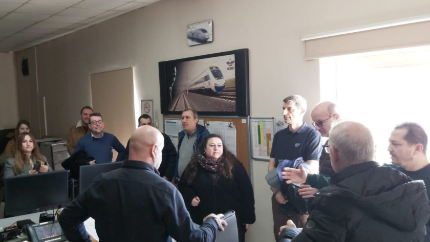 Professionals gathered around a control room discussing train operations